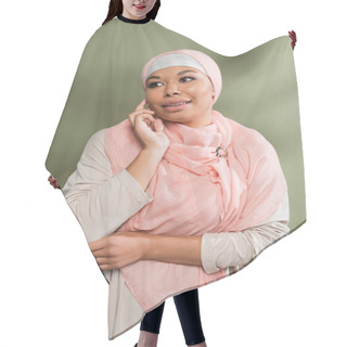Personality  Stylish Multiracial Woman In Abaya Dress And Pink Hijab Touching Face And Looking Away On Green Background Hair Cutting Cape