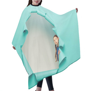 Personality  Scared Red Haired Preteen Girl In Blue T-shirt Looking At Camera While Standing Behind Hole In Blue Paper On White Background Background Hair Cutting Cape