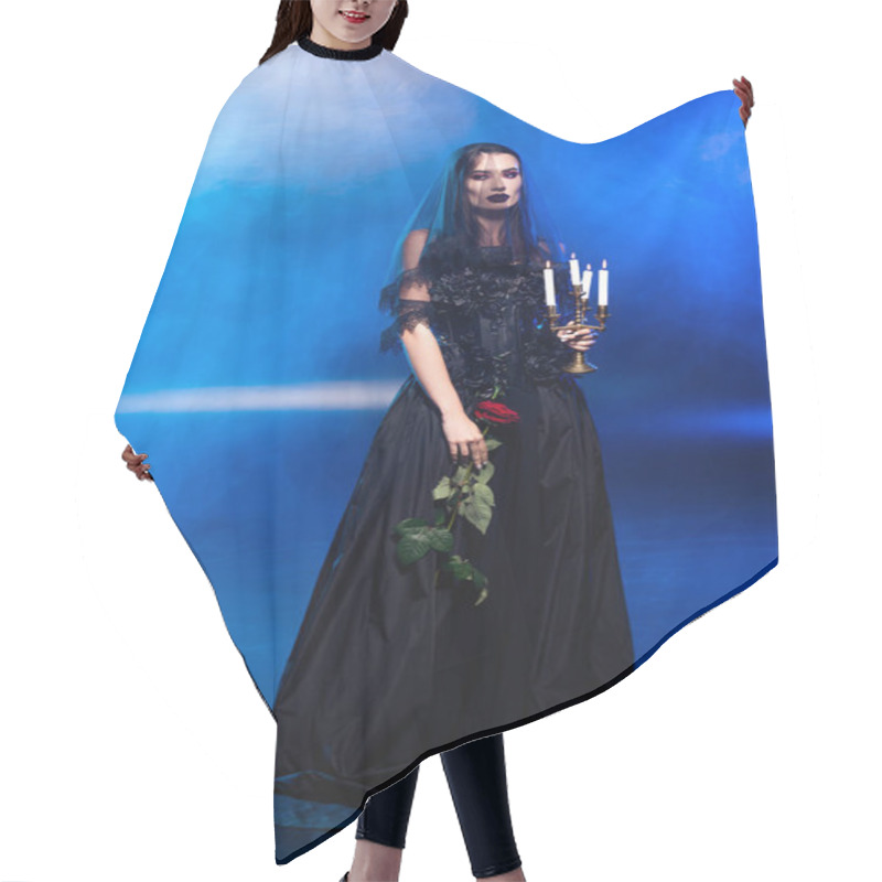 Personality  bride in black dress and veil holding rose and candles on blue with smoke, halloween concept hair cutting cape
