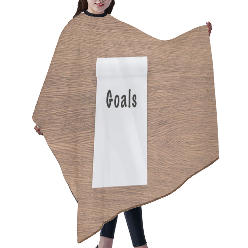 Personality   top view of notebook with 'goals' lettering on wooden background  hair cutting cape