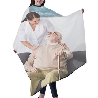 Personality  Smiling Elderly Man Sitting On Sofa With Walking Stick And Looking At Social Worker Hair Cutting Cape