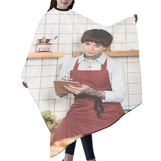 Personality  Selective Focus Of Pretty Barista In Apron Writing In Notebook And Looking At Camera Hair Cutting Cape