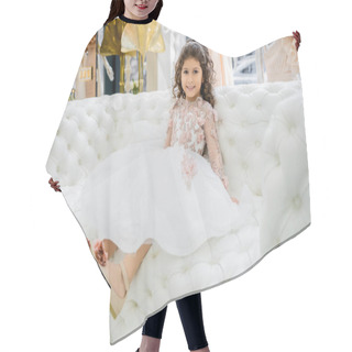 Personality  Cheerful Middle Eastern Girl With Curly Hair Sitting In Floral Dress With Tulle Skirt And Shoes On White Couch Inside Of Luxurious Wedding Salon, Smiling Kid, Blurred Background  Hair Cutting Cape