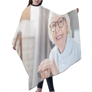 Personality  Portrait Of Happy Mature Woman In Eyeglasses Holding Cane While Sitting On Sofa At Home Hair Cutting Cape