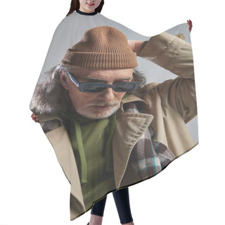 Personality  Portrait Of Senior And Bearded Man In Dark Sunglasses, Beige Trench Coat And Plaid Scarf Adjusting Beanie Hat On Grey Background, Hipster Style, Fashionable Aging Concept Hair Cutting Cape