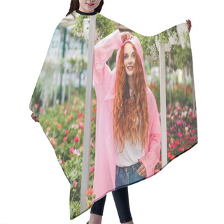 Personality  Pretty Smiling Lady With Redhead Curly Hair Standing In Pink Raincoat And Dreamily Looking In Camera While Spending Time In Greenhouse With Beautiful Flowers On Background Hair Cutting Cape