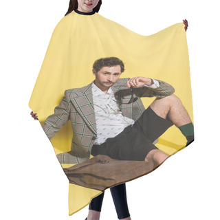 Personality  Charming Guy In Jacket Holding Sunglasses And Sitting Near Bag On Yellow Background  Hair Cutting Cape