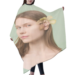 Personality  Vertical Close-up Studio Portrait Of Young Caucasian Woman With Clean Girl Look And Fresh Orchid Flower In Hair Looking At Camera Hair Cutting Cape