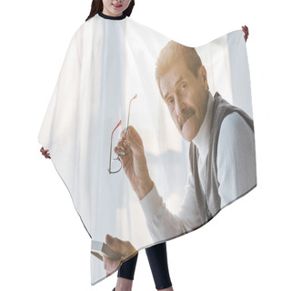 Personality  Sad Pensioner Holding Glasses And Looking At Camera While Sitting At Home Hair Cutting Cape