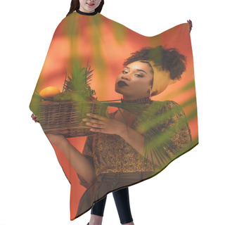 Personality  Young African American Woman Holding Basket With Exotic Fruits Behind Blurred Palm Leaves On Orange Hair Cutting Cape