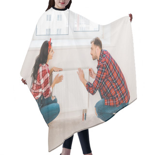 Personality  Cheerful Couple Touching Heating Radiator While Sitting Near Window At Home Hair Cutting Cape