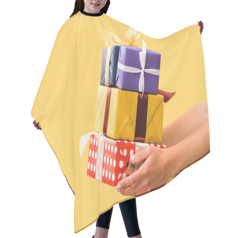 Personality  partial view of girl holding gift boxes isolated on yellow hair cutting cape