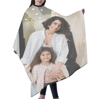 Personality  Joyful Middle Eastern Woman With Brunette Hair Holding Shopping Bags And Hugging Cute Little Girl While Standing Near Wedding Dresses In Bridal Salon, Mother And Daughter, Bridal Shopping  Hair Cutting Cape
