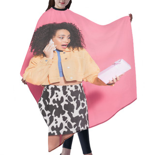 Personality  Amazed Curly African American Woman In Crop Top And Jacket Talking On Smartphone And Holding Present On Pink  Hair Cutting Cape