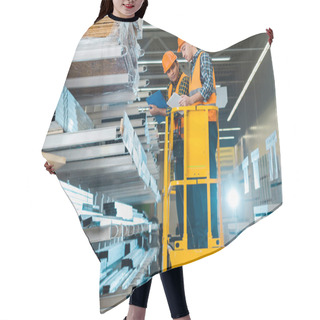 Personality  Multicultural Workers With Digital Tablet And Clipboard Standing On Scissor Lift Near Shelves With Metallic Construction Materials Hair Cutting Cape