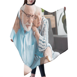 Personality  Senior Woman Hugging Sad Husband On Couch At Home Hair Cutting Cape