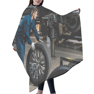 Personality  Young Mechanic Holding Car Wheel Near Raised Car In Workshop Hair Cutting Cape