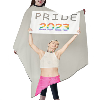 Personality  Tattooed And Positive Gay Man In Baseball Cap, Crop Top, And Pink Pants Holding Pride 2023 Placard Above Head While Standing And Looking At Camera On Grey Background  Hair Cutting Cape