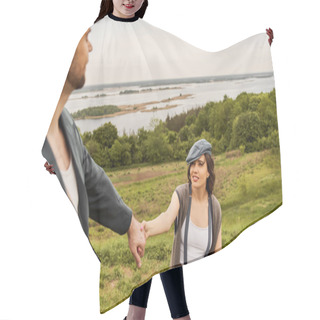 Personality  Smiling And Trendy Brunette Woman In Suspenders And Newsboy Cap Holding Hand Of Blurred Boyfriend In Jacket While Standing With Nature And Sky At Background, Fashionable Couple In Countryside Hair Cutting Cape