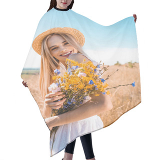 Personality  Young Stylish Woman In Straw Hat Holding Wildflowers While Looking At Camera In Grassy Field Hair Cutting Cape