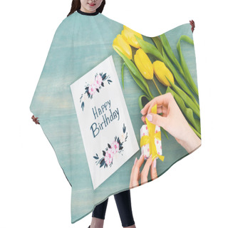 Personality  Cropped View Of Woman Holding Gift Box Near Greeting Card With Happy Birthday Lettering And Yellow Tulips On Blue Wooden Surface  Hair Cutting Cape