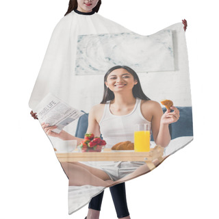Personality  Selective Focus Of Asian Girl Smiling At Camera While Holding Newspaper And Croissant On Bed  Hair Cutting Cape