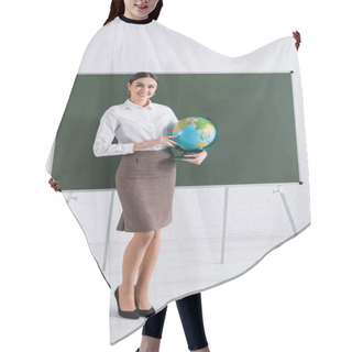 Personality  Young Teacher Holding Globe And Smiling At Camera Near Chalkboard In School  Hair Cutting Cape