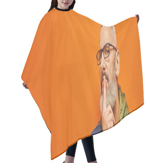 Personality  Focused Mature Man In Green Hoodie With Glasses And Gray Beard Posing On Orange Background, Banner Hair Cutting Cape