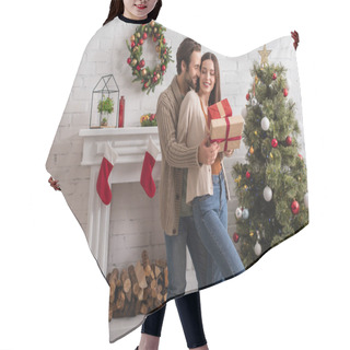 Personality  Man Embracing Happy Wife Holding Presents Near Christmas Tree And Decorated Fireplace Hair Cutting Cape