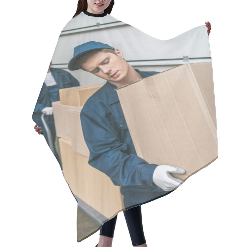 Personality  two handsome movers in uniform transporting cardboard boxes with hand truck in warehouse hair cutting cape