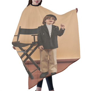 Personality  Inspired Boy Standing Near Director Chair, With A Smile On Face Showing Idea Sign,  Profession Hair Cutting Cape