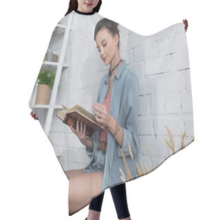 Personality  Brunette Woman Reading Book Near Rack With Wicker Baskets And White Brick Wall Hair Cutting Cape