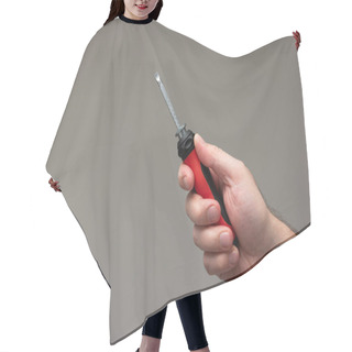 Personality  Caucasian Male Hand Holding A Red Plastic Handle Screwdriver Isolated On Gray Background. Hair Cutting Cape