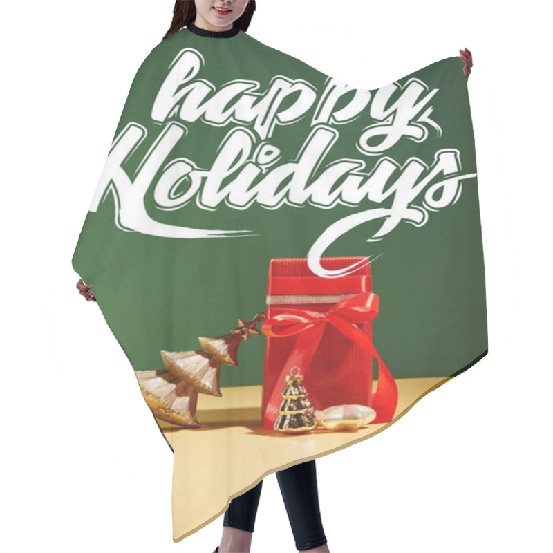 Personality  red gift box and decorative Christmas tree with golden baubles on green background with white happy holidays lettering hair cutting cape