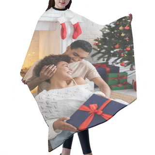 Personality  Smiling African American Man Sitting Near Fireplace With Happy Girlfriend Holding Christmas Present Hair Cutting Cape