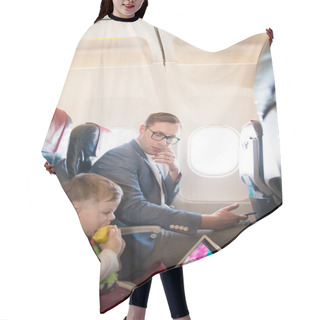 Personality  The Elegant Young Father Sitting On A Plane Near The Cute Little Son Who Is Eating An Apple And Using The Tablet Hair Cutting Cape
