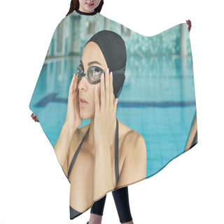 Personality  A Young Woman In A Swimsuit And Goggles Holds Her Hands Up To Her Face In An Indoor Spa Pool. Hair Cutting Cape