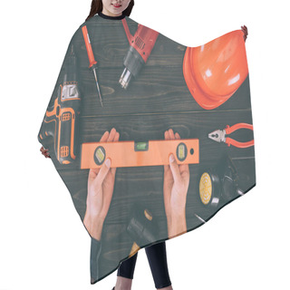 Personality  Cropped Shot Of Worker Holding Spirit Level And Various Supplies On Wooden Tabletop Hair Cutting Cape