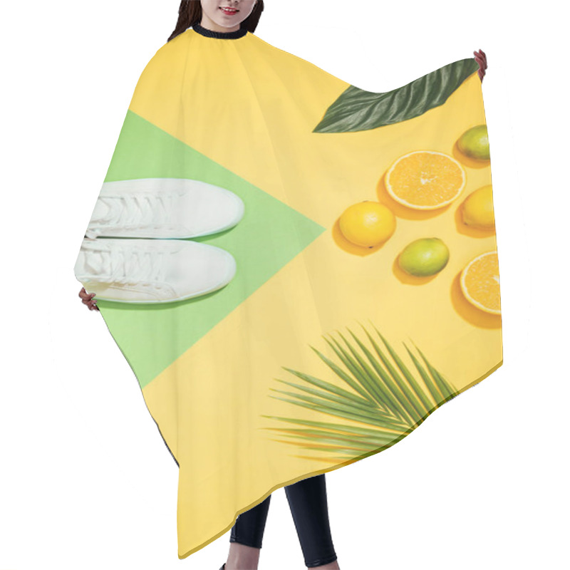 Personality  top view of stylish female sneakers, tropical leaves, lemons, limes and slices of orange hair cutting cape