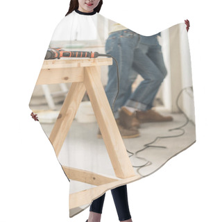 Personality  Electric Drill On Wooden Table And Young Couple Standing Near Wall Behind Hair Cutting Cape
