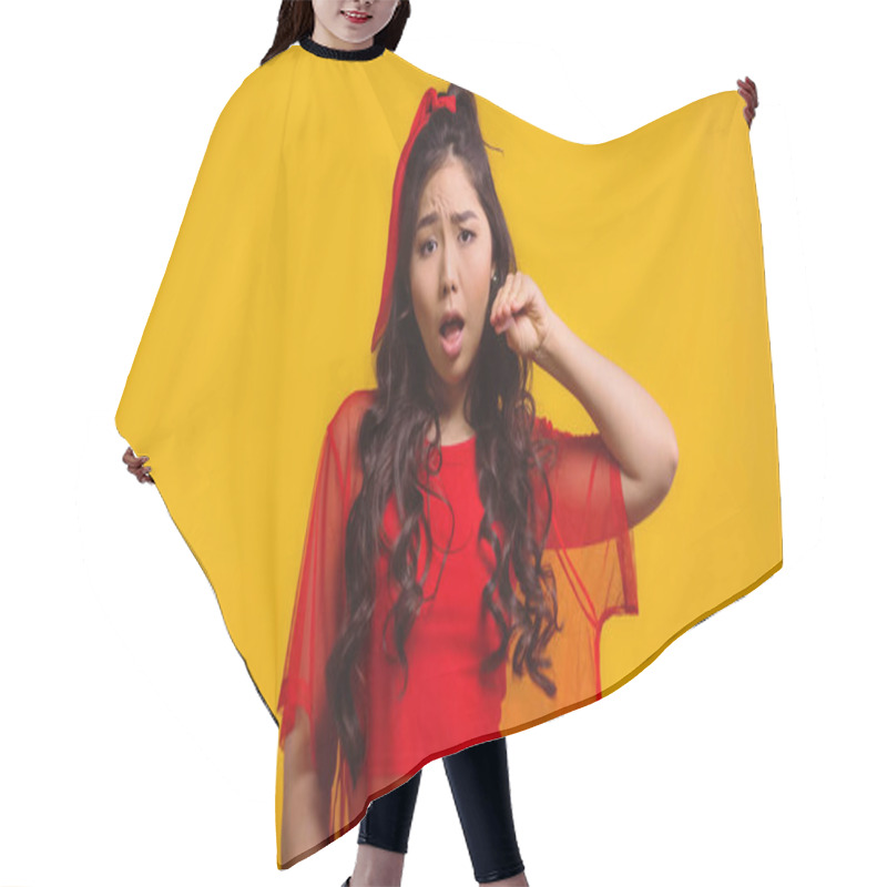 Personality  displeased asian woman showing blah blah gesture isolated on yellow hair cutting cape