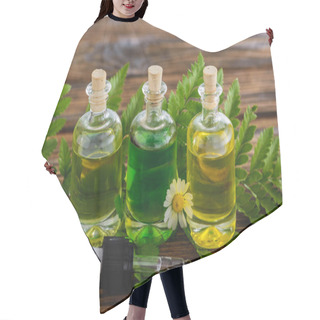 Personality  Corked Bottles With Essential Oils, Dropper, Fern Leaves And Chamomile Flower On Wooden Surface Hair Cutting Cape