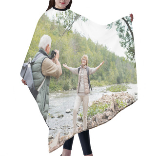 Personality  Cheerful Aged Active Woman With Outstretched Arms Looking At Her Husband With Camera While Both Standing By River Hair Cutting Cape