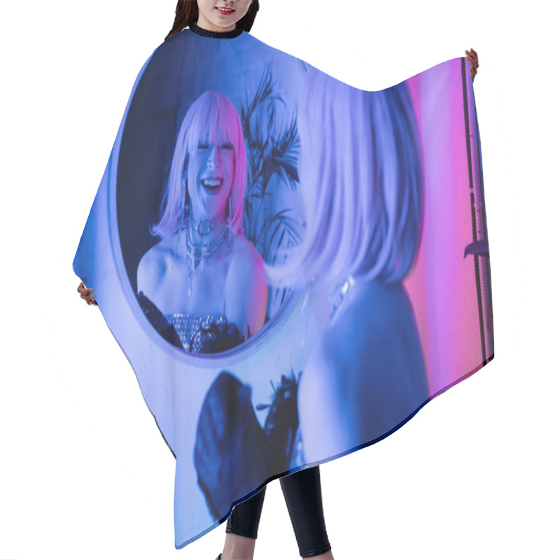 Personality  Cheerful Drag Queen In Wig And Top Looking At Mirror In Neon Light At Home  Hair Cutting Cape