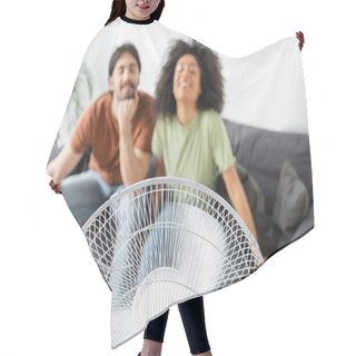 Personality  Blurred And Happy Interracial Couple Sitting On Couch Near Electric Fan In Living Room  Hair Cutting Cape