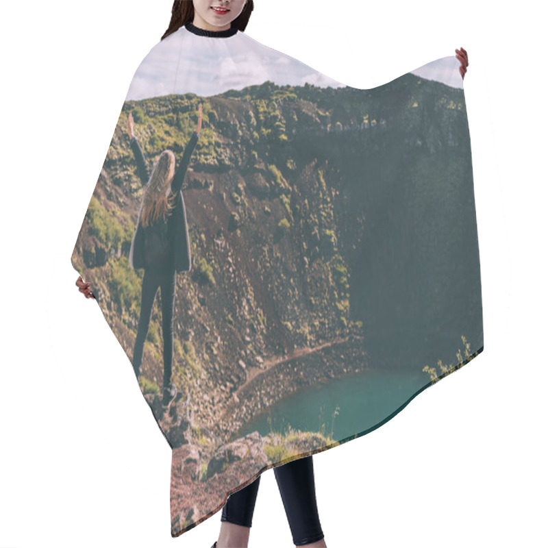 Personality  back view of girl standing with raised hands and looking at beautiful crater lake in Iceland hair cutting cape