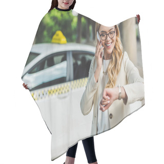 Personality  Smiling Blonde Woman In Eyeglasses Talking By Smartphone And Checking Wristwatch While Standing Near Taxi Cab   Hair Cutting Cape