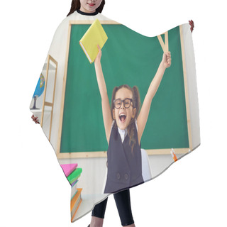 Personality  Back To School. Little Happy Schoolchild Raised Hands Up Against The Background Of A Green Blackboard In A Classroom. Hair Cutting Cape