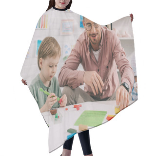Personality  Portrait Of Teacher And Adorable Preschooler With Plasticine Sculpturing Figures At Table In Classroom Hair Cutting Cape