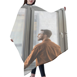 Personality  Brunette And Bearded Businessman In Stylish Eyeglasses And Fashionable Shirt, Confident And Successful, Standing At Large Window In Office And Looking Away Hair Cutting Cape